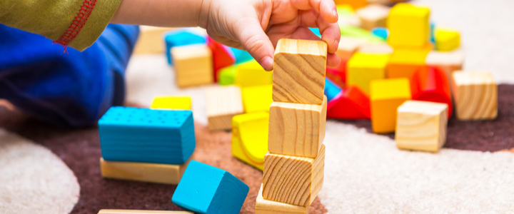 A child’s hand stacking wooden blocks on top of each other