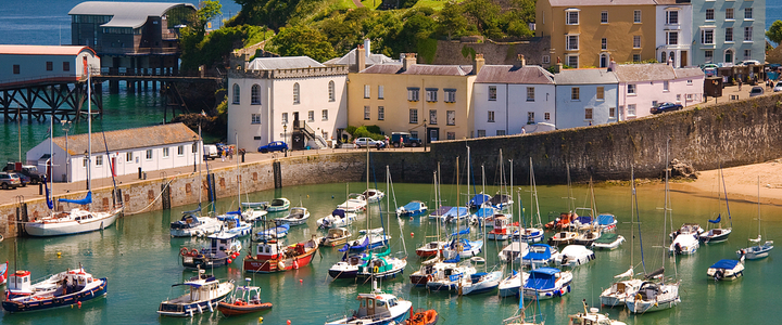 Tenby harbour with boats in the sea and brightly coloured houses behind