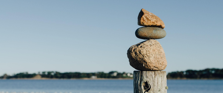 Three rocks balanced on a wooden post on a UK beach