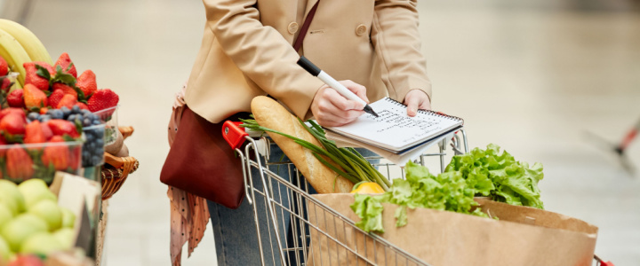 Woman pushing a trolley and ticking items off a shopping list