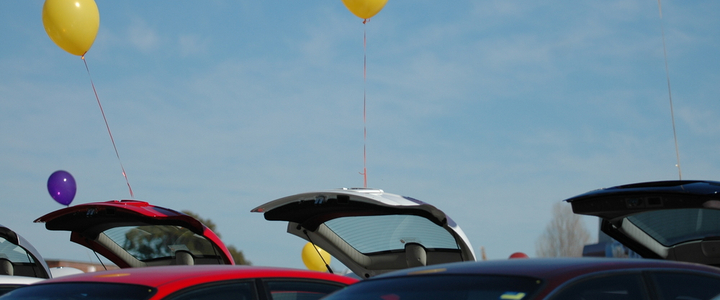 Balloons tied to the open boots of cars