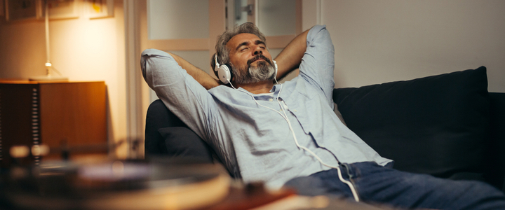 A man with headphones relaxing on a sofa