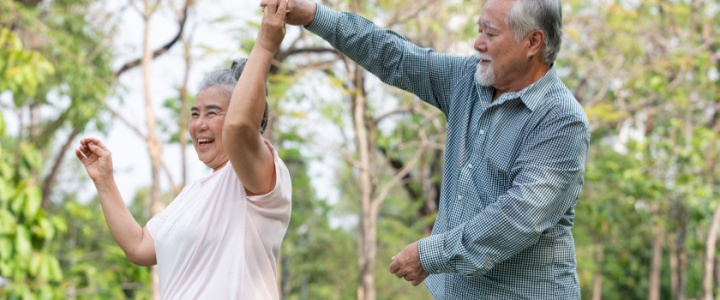 Older couple dancing outside.