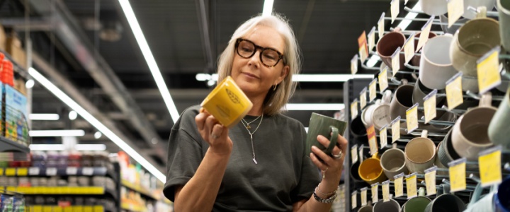 A woman deciding between which mug to buy.